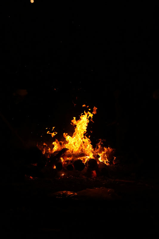 A fire is lit in the dark with bright orange flames