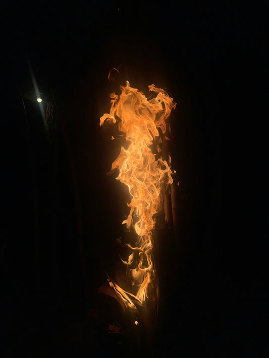 A person standing in the dark with a fire in their hand