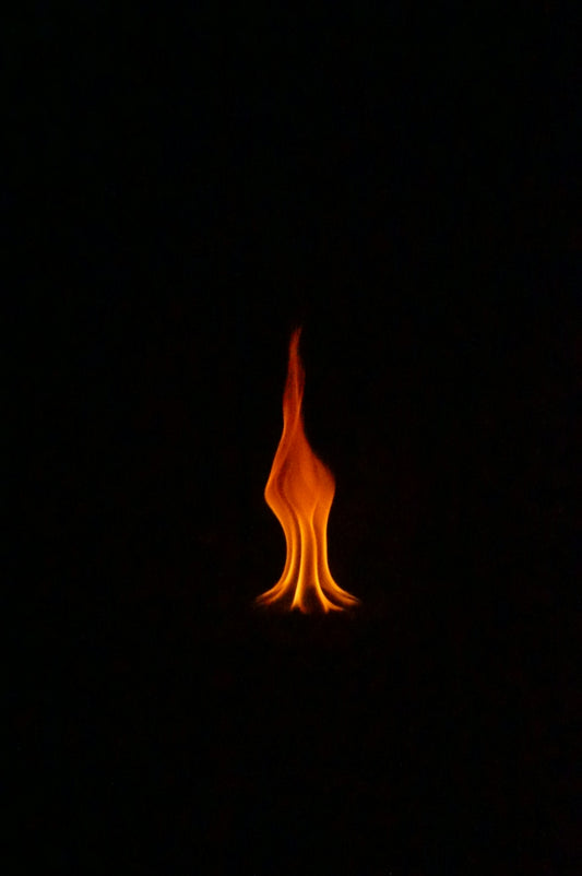 A single flame of fire burns in darkness