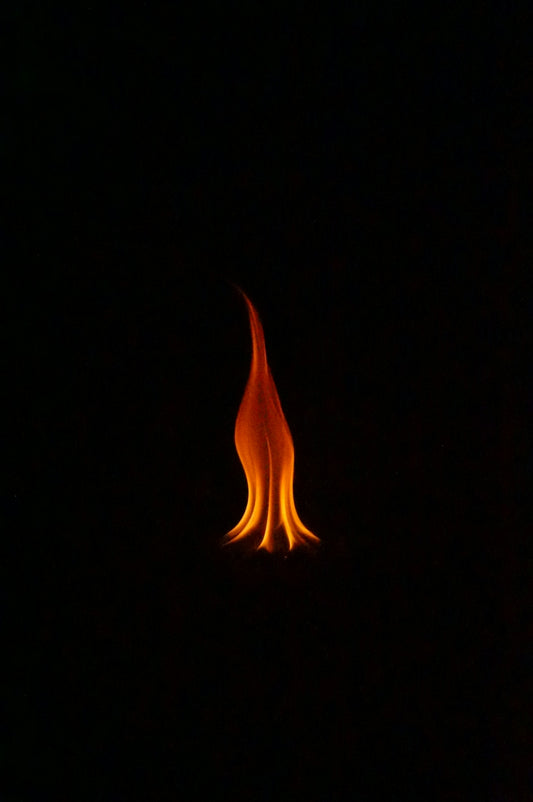 A single flame burns brightly against black