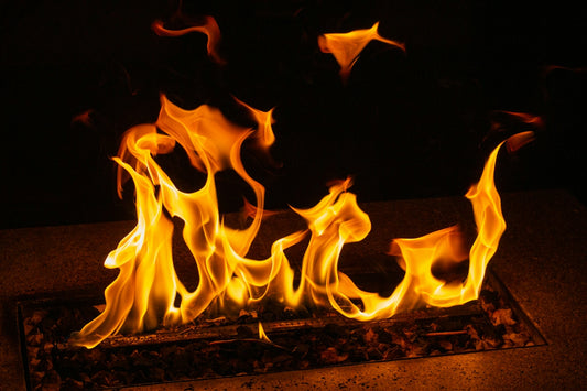 Bright orange flames rising from a dark stone fire pit at night